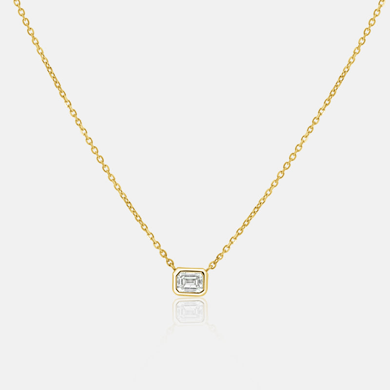 East West emerald cut bezel set diamond pendant necklace with one .18 carat diamond