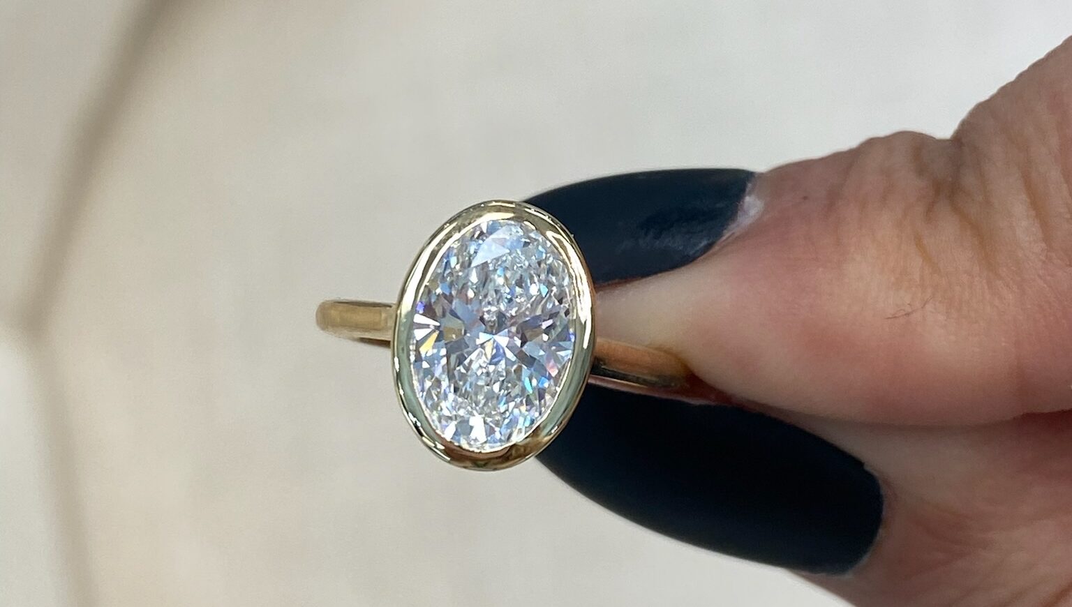 Yellow gold band, oval cut diamond, bezel set engagement ring at Masina Diamonds.