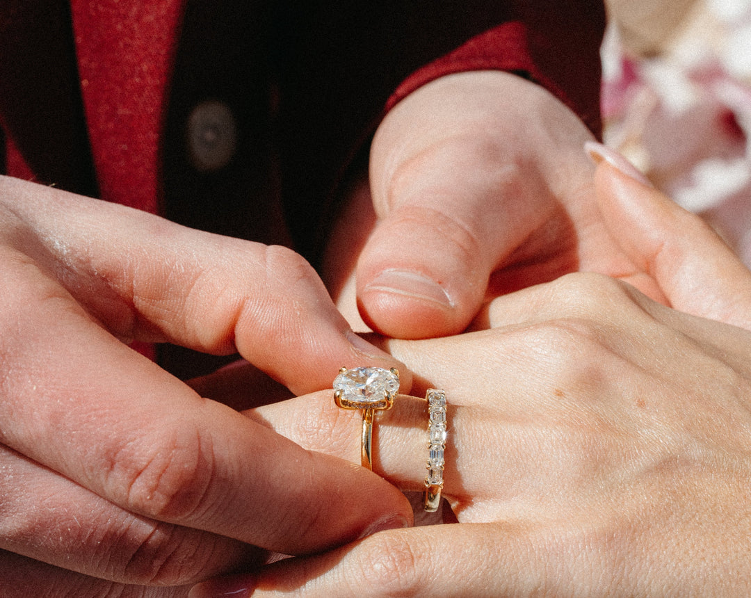 oval diamond solitaire engagement ring with emerald cut band set in yellow gold