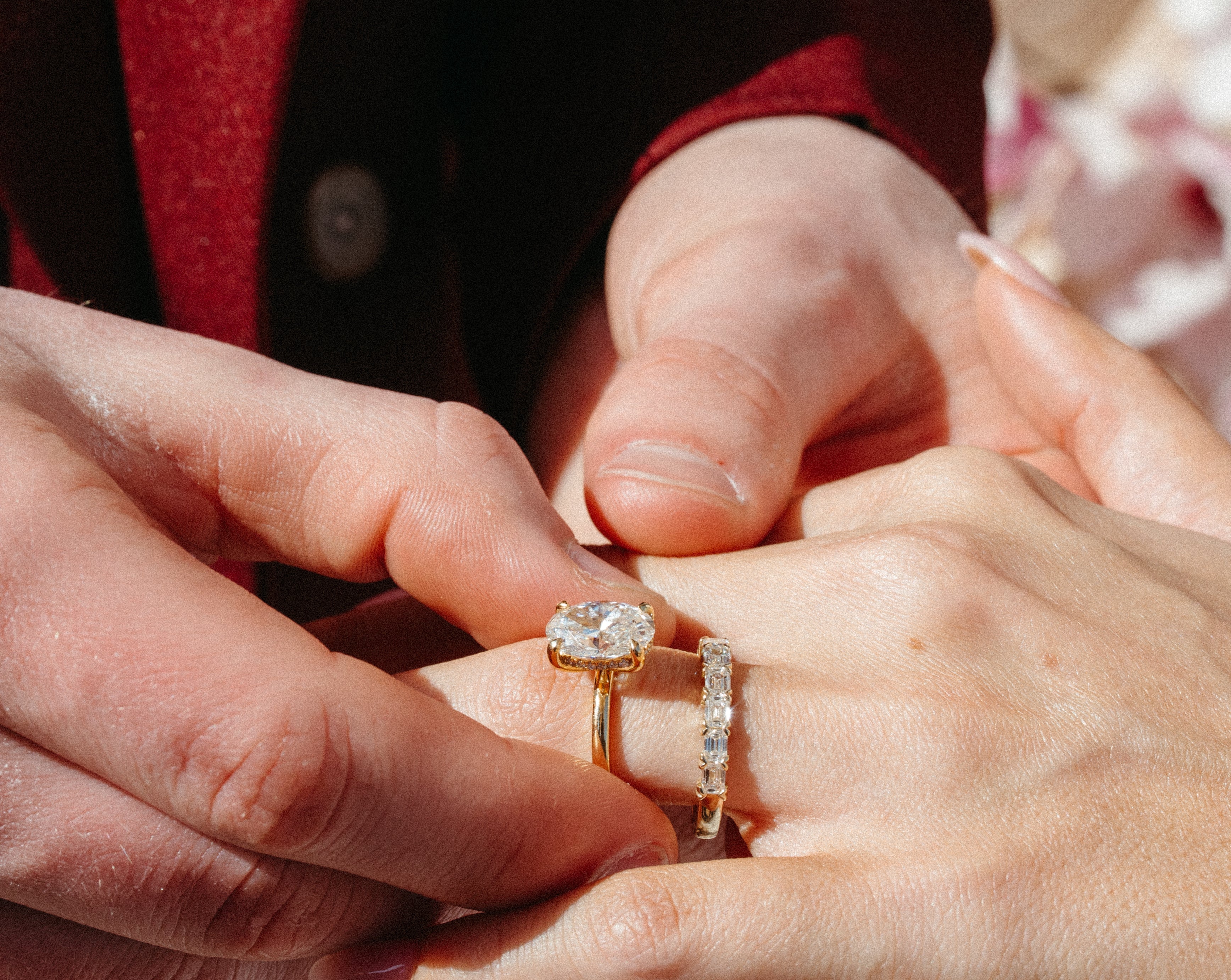 Diamond engagement ring and wedding band being placed on a finger.