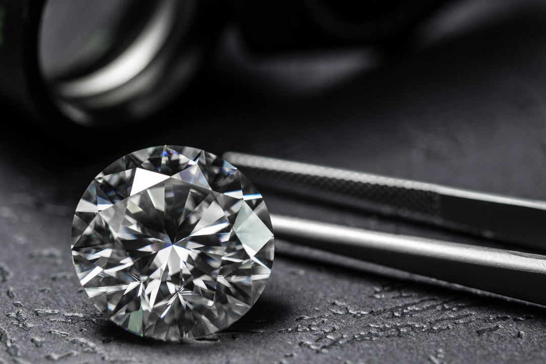 Lab-created round cut diamond with tweezers.