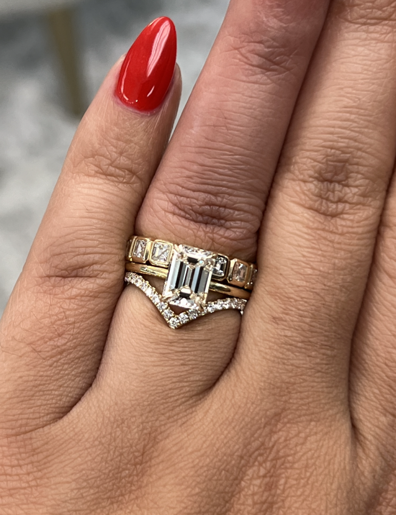 Gold ring stack with emerald-cut engagement ring.