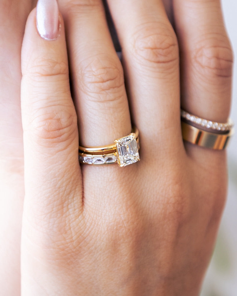 Hand wearing a yellow gold engagement and wedding ring.
