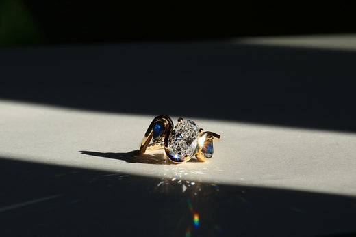 Oval diamond engagement ring with sapphire accents.