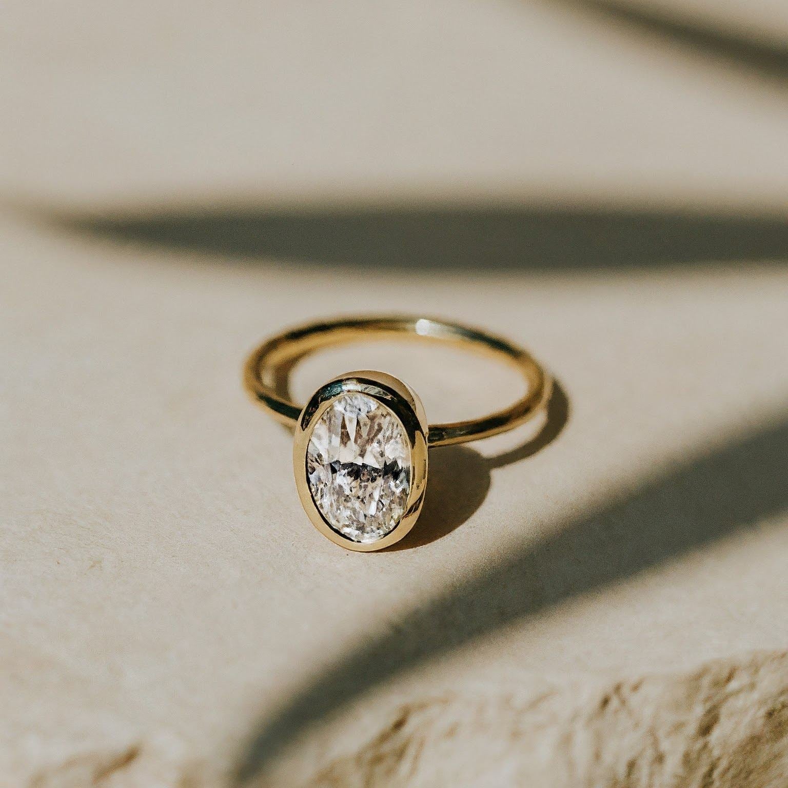 Oval diamond bezel set gold ring.