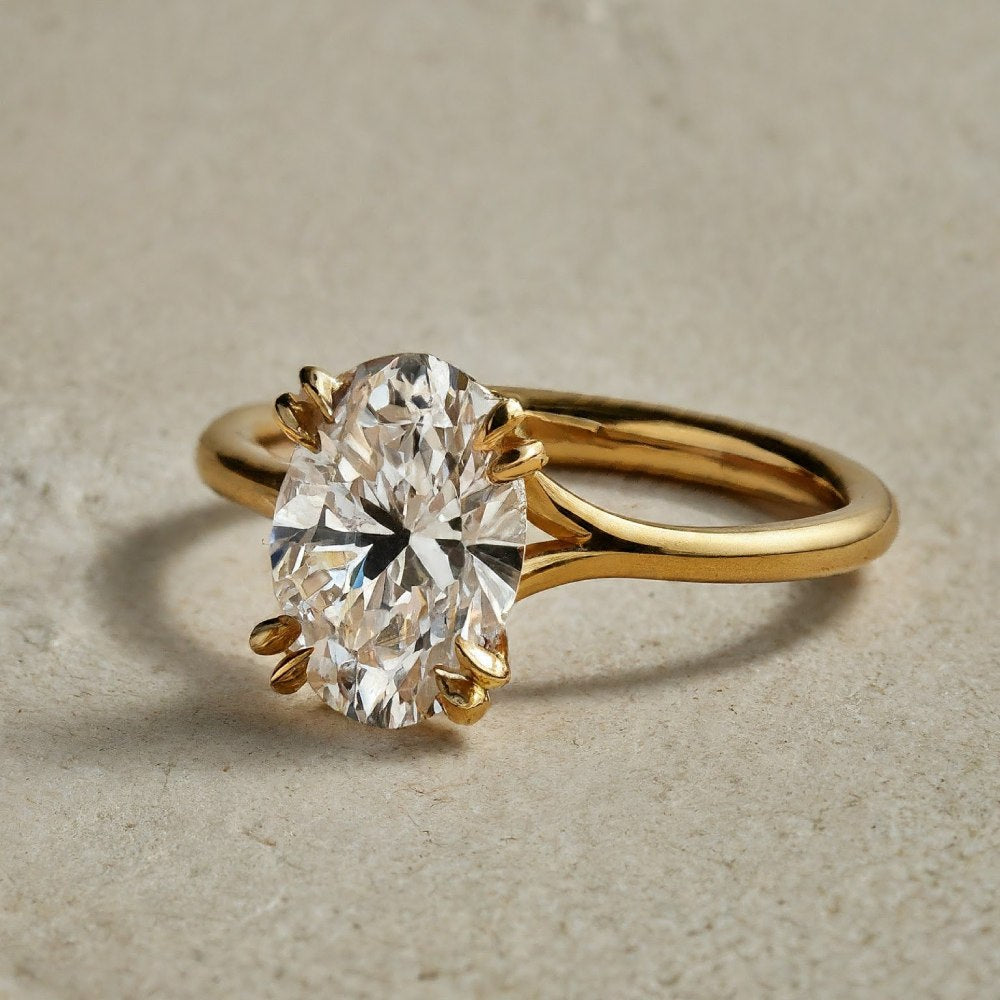 Close-up of a gold oval diamond engagement ring, highlighting the prongs.