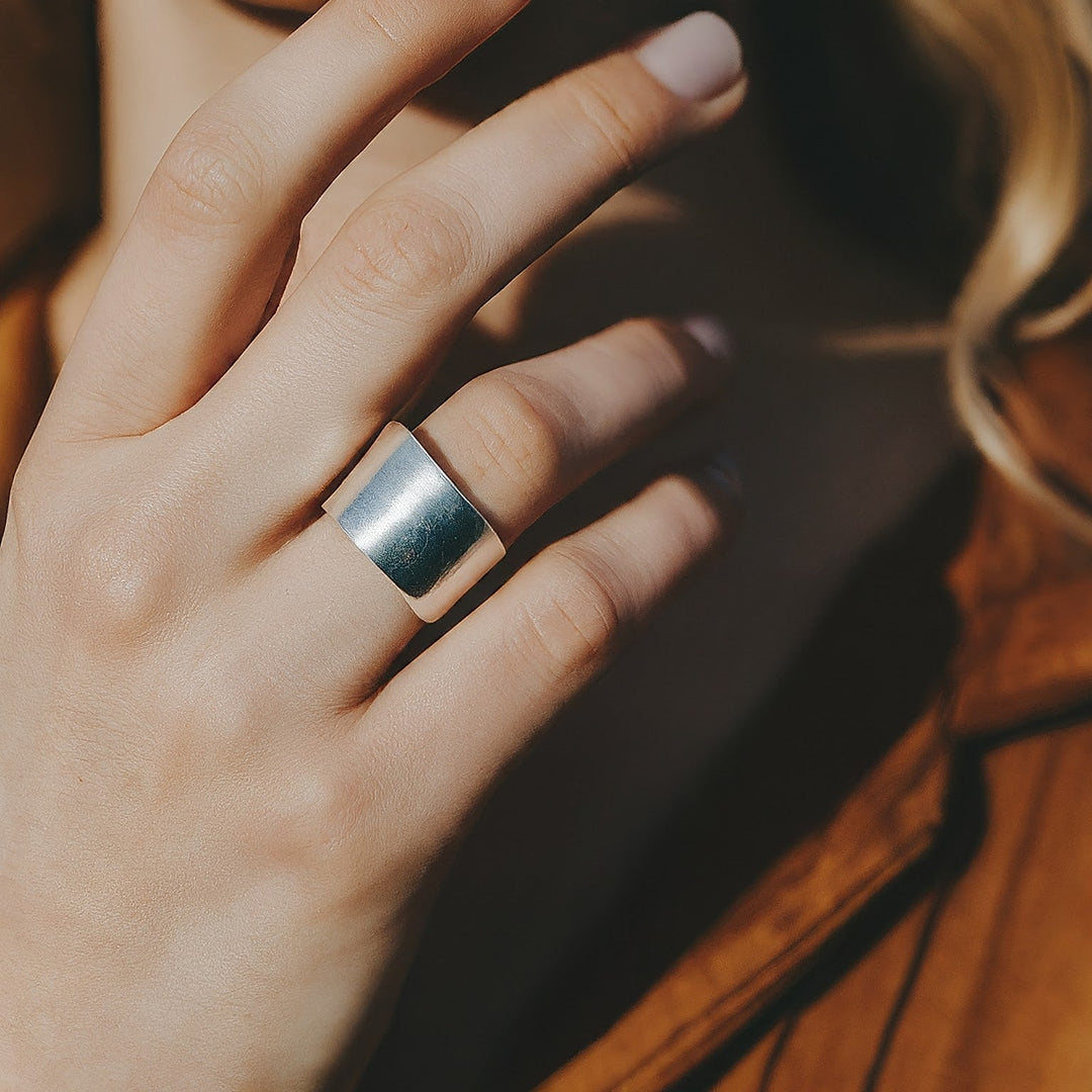 Woman's hand wearing a sterling silver band ring.