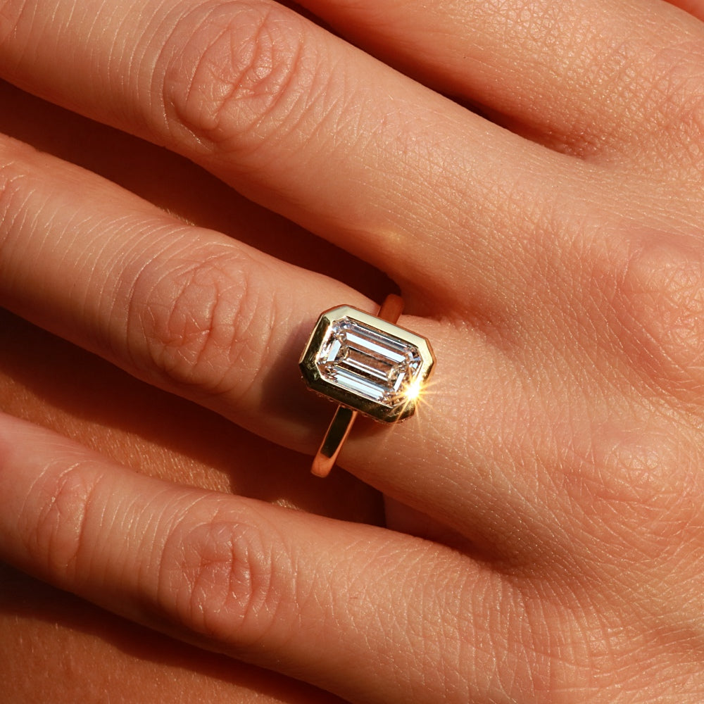 Close-up of hand wearing Masina Diamonds gold emerald-cut engagement ring
