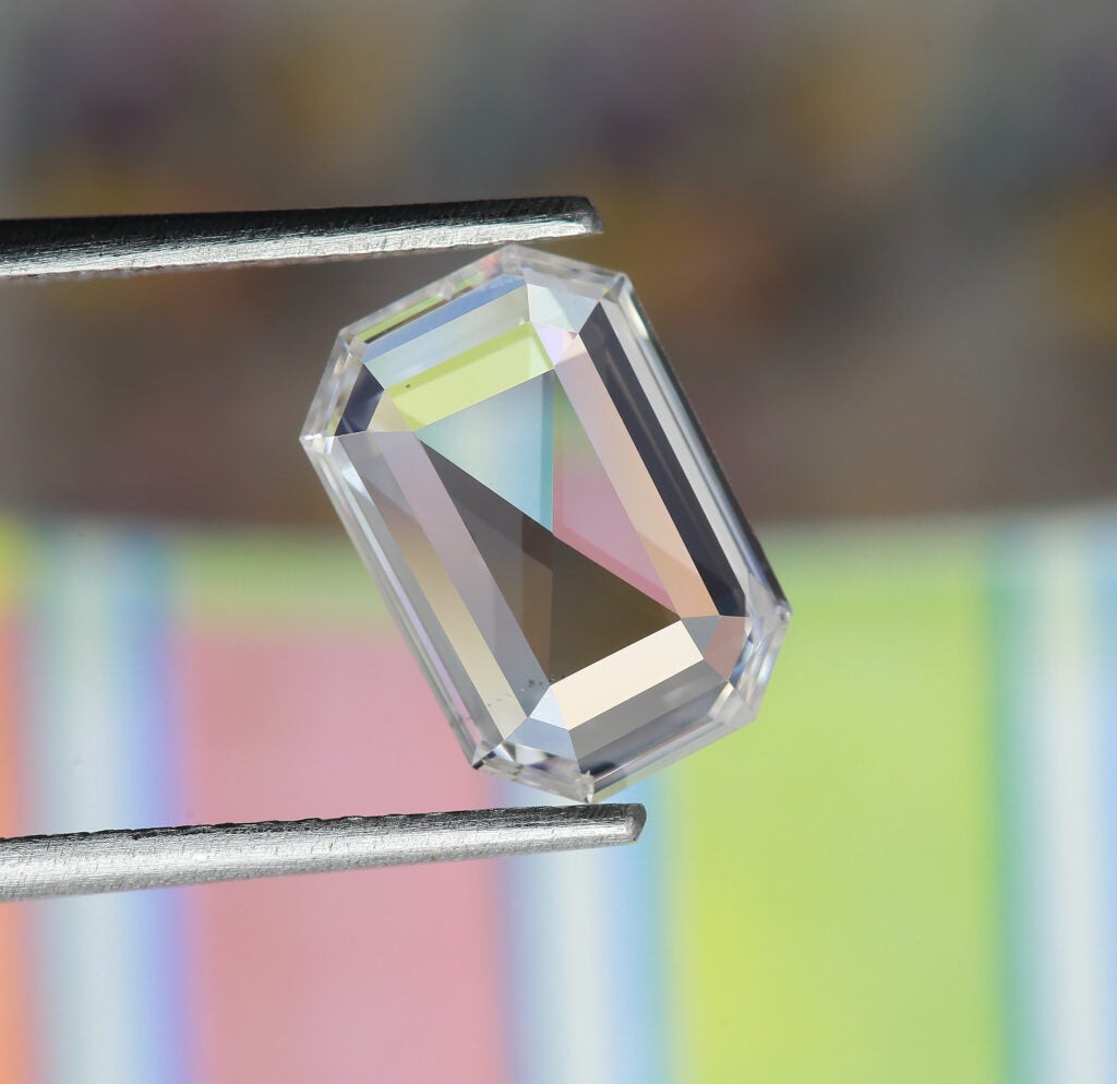 Emerald cut diamond in tweezers.