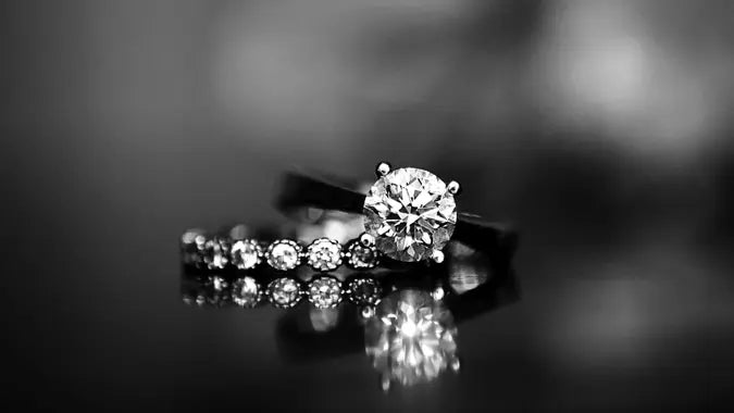 Masina Diamond engagement ring reflecting on black surface.