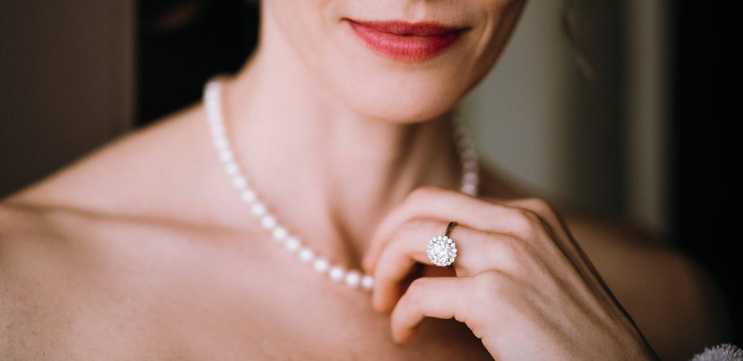 Bride wearing pearl necklace and diamond ring.