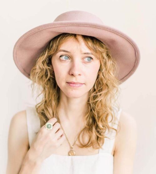 Woman wearing an emerald ring and hat for travel engagement inspiration.