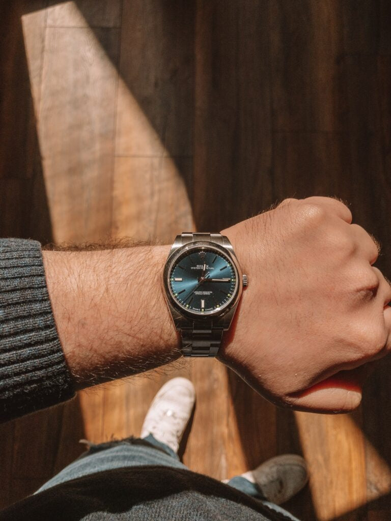 Rolex watch on wrist with stainless steel bracelet.