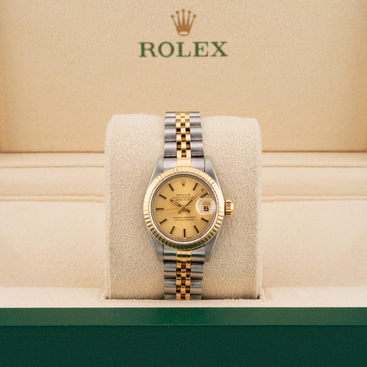 Rolex watch with gold and silver band on a cushion with Rolex logo in the background
