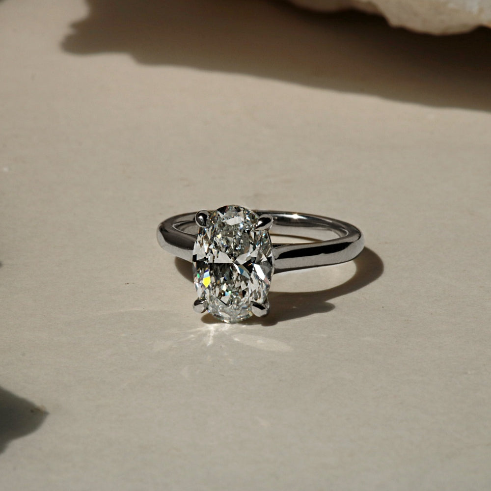 Oval solitaire cathedral engagement ring in white gold