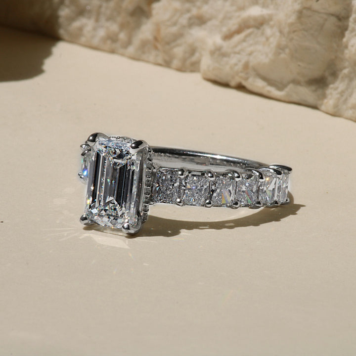 Emerald cut engagement ring with radiant cut diamond band and hidden halo