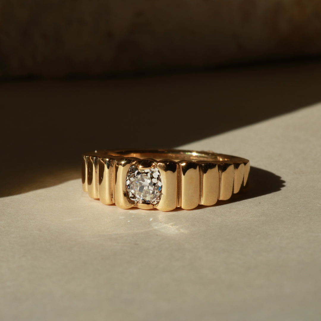 Gold ring with a diamond on a textured surface