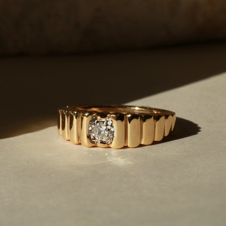 Gold ring with a diamond on a textured surface