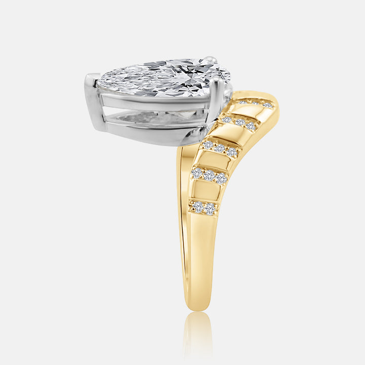 A pear-cut diamond engagement ring featuring a silver-toned prong setting and a yellow gold band with pavé-set diamonds, shown on a light gray background.