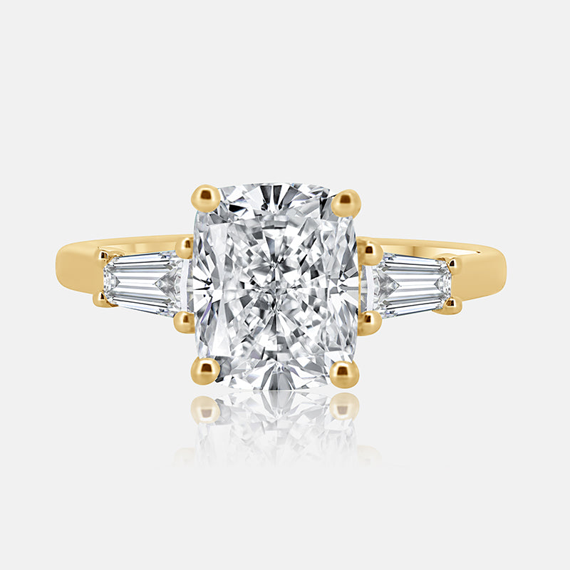 yellow gold three stone engagement ring with cushion cut center diamond and tapered baguettes on the side