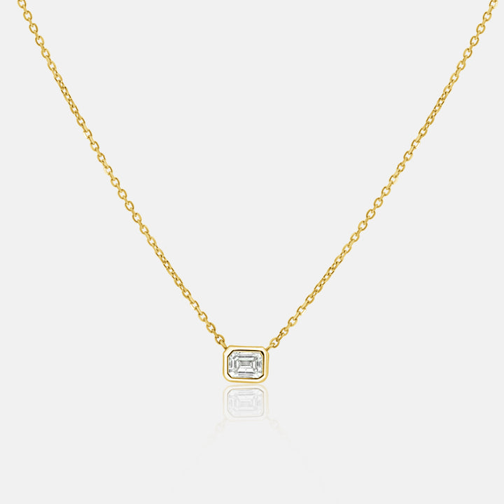 East West emerald cut bezel set diamond pendant necklace with one .18 carat diamond