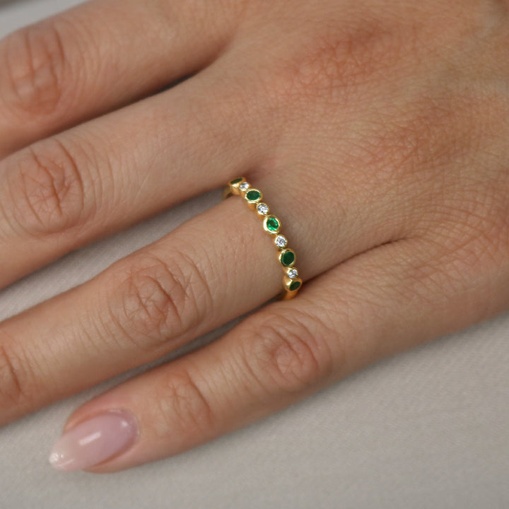 Emerald and diamond stackable wedding band in yellow gold on hand